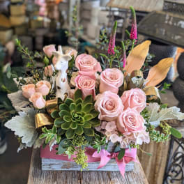 Pink roses and succulents arranged in a wooden box with a giraffe figurine