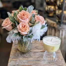 Peach roses in a textured glass vase beside a pale yellow candle.