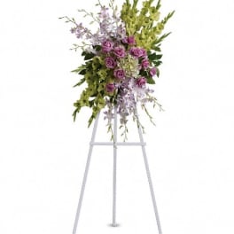 Standing floral spray with purple roses and green orchids on an easel