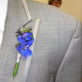 Blue orchid boutonniere pinned to a gray suit jacket