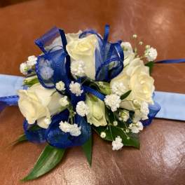 White rose corsage with blue ribbon and baby's breath