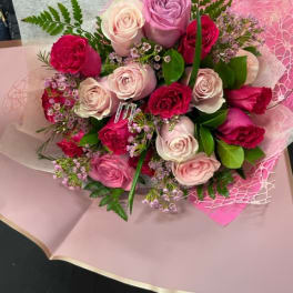 Bouquet of pink, lavender, and white roses wrapped in pink paper