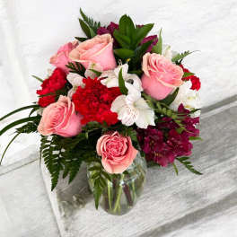 Pink roses and red flowers arranged in a glass vase