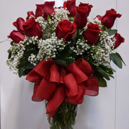 Red roses with baby's breath in a glass vase and red ribbon
