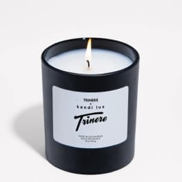 Lit black scented candle in a glass jar with a white label