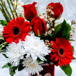 Red roses and gerbera daisies in a red heart vase