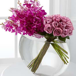 Pink roses and magenta orchids in a clear glass vase