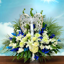 White and blue floral arrangement with a decorative angel wing topper