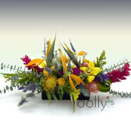 Colorful tropical flower arrangement in a low rectangular container