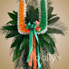 Large standing floral tribute with orange and green garlands and ribbon bow