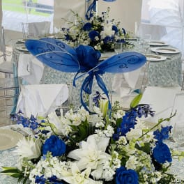 Blue and white floral centerpieces with butterfly decorations on round tables