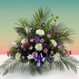 Large floral arrangement with pink, white, and purple flowers and palm fronds