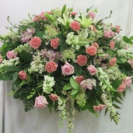 Large horizontal spray of pink roses and carnations with white lilies and other white flowers