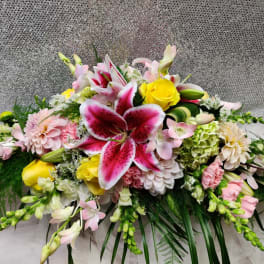 Large floral arrangement with pink lilies, yellow roses, and pastel blooms