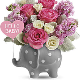 Pink and white roses in a gray elephant planter with a "Hello Baby!" balloon