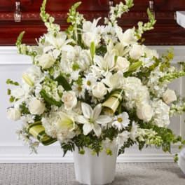 White floral arrangement in a white vase with lilies and roses