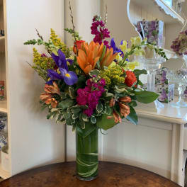 Colorful mixed flower arrangement in a tall glass vase