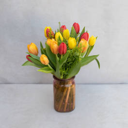 Bouquet of red, yellow, and orange tulips in a brown glass vase