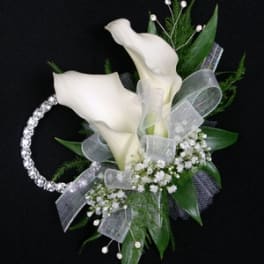 White calla lily corsage with baby's breath and silver ribbon on a black background