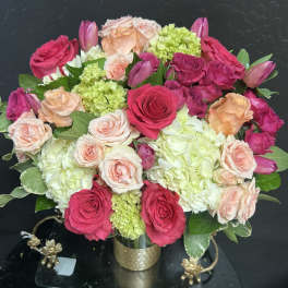 Bouquet of pink and peach roses with hydrangeas in a gold vase