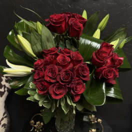 Bouquet of red roses with lily buds in a glass vase
