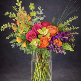 Colorful bouquet of roses, orchids, and snapdragons in a clear glass vase