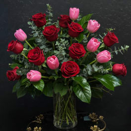 Red roses and pink tulips in a clear glass vase