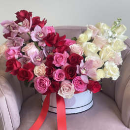 Large bouquet of red, pink, and white roses with orchids in a round box