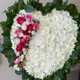 Heart-shaped white chrysanthemum wreath with pink roses and a green leaf border