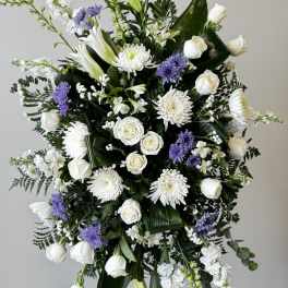 White and purple funeral spray with roses, lilies, and chrysanthemums
