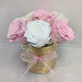 Small arrangement of pink and white roses in a gold vase with a pink ribbon bow
