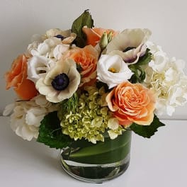 Bouquet of peach, white, and cream flowers in a glass vase