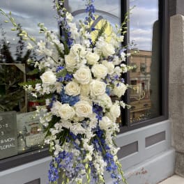 Tall floral spray with white roses and blue flowers on a stand
