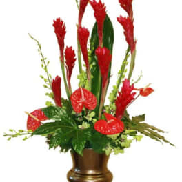 Red tropical flowers arranged in a bronze pedestal vase
