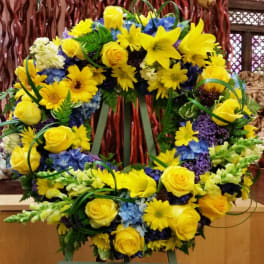 Yellow flower wreath with blue accents on a stand