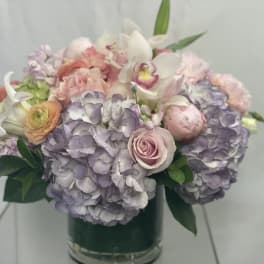 Pastel bouquet of hydrangeas, roses, and orchids in a glass vase
