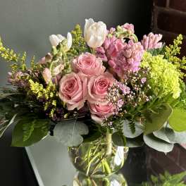 Pink roses and white tulips in a clear glass vase