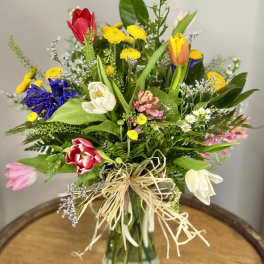 Mixed bouquet of colorful tulips and small flowers in a glass vase
