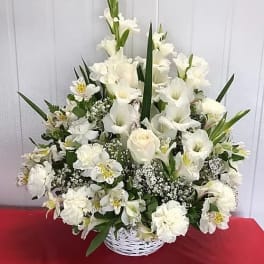 White floral arrangement in a white basket with tall blooms and greenery