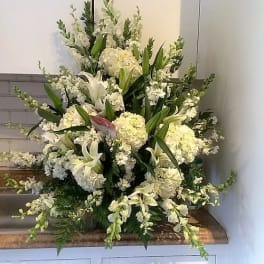 Large white floral arrangement with lilies and hydrangeas