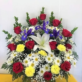 Large mixed flower arrangement with red roses, white lilies, and daisies