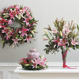 Pink lily arrangements with a matching wreath and vase centerpiece