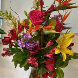 Mixed bouquet with roses, lilies, and bird-of-paradise in a glass vase