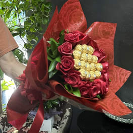 Bouquet of red roses with gold-wrapped chocolates in red wrapping