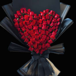 Heart-shaped bouquet of red roses wrapped in black paper