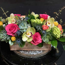 Pink roses and pale orchids in a wooden box with succulents