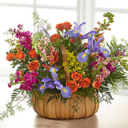 Mixed bouquet in a pumpkin-shaped container with orange, purple, and pink flowers
