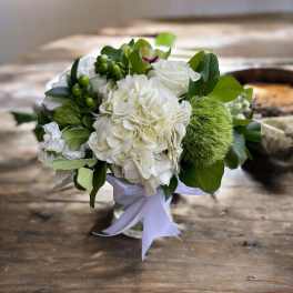 White floral bouquet with green accents and a white ribbon