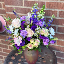 Bouquet of purple, pink, and white flowers in a frosted glass vase