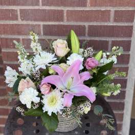 Pink lily and pale roses arranged in a striped vase